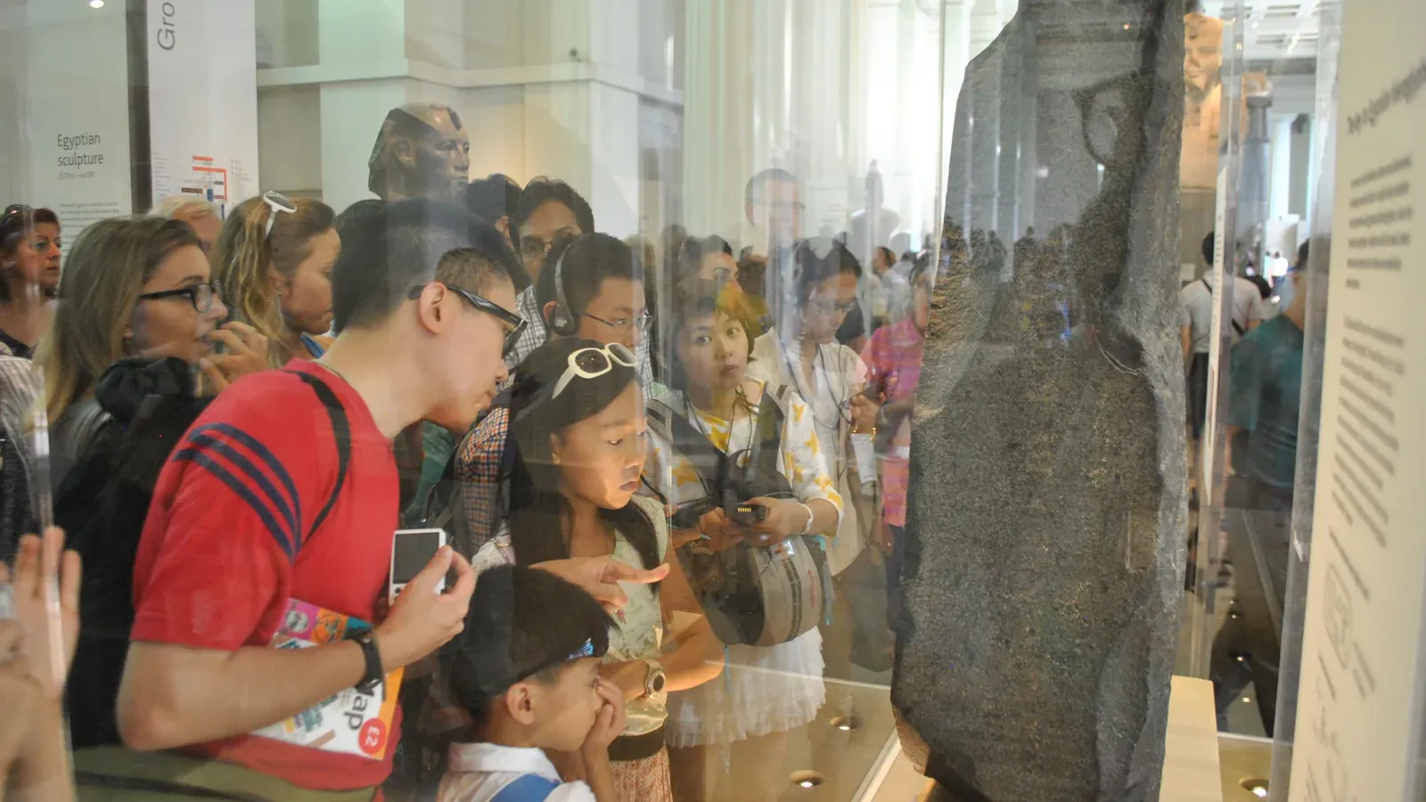 Visitor looking at the Rosetta Stone on display at the British Museum in London